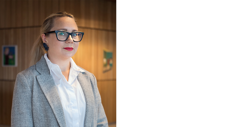 porträttbild på kvinna med glasögon, grå kavaj och röda läppar