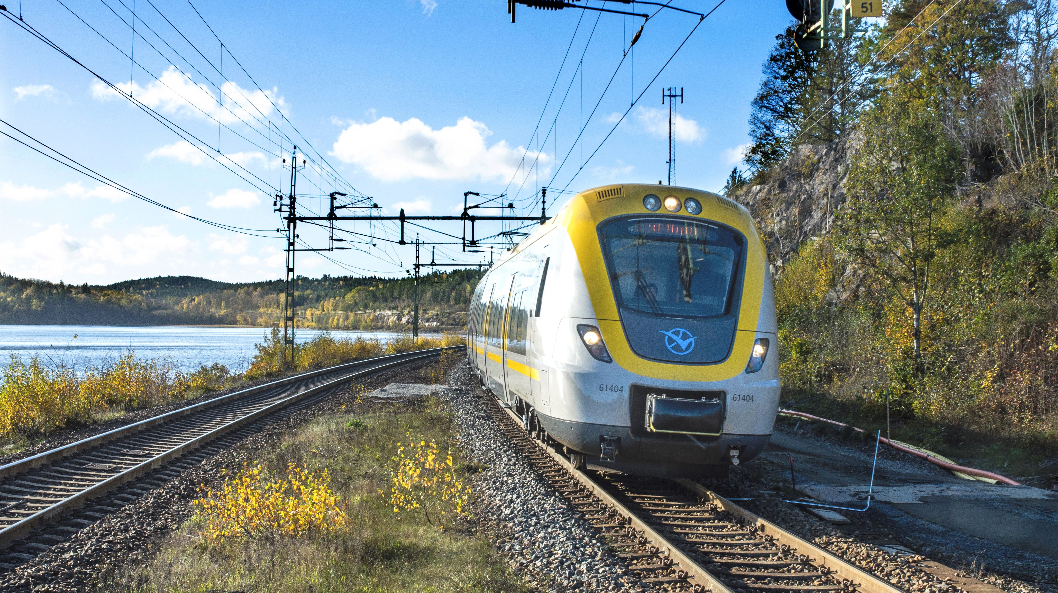 Ett tåg som åker på en dubbelspårig räls vid en sjö.