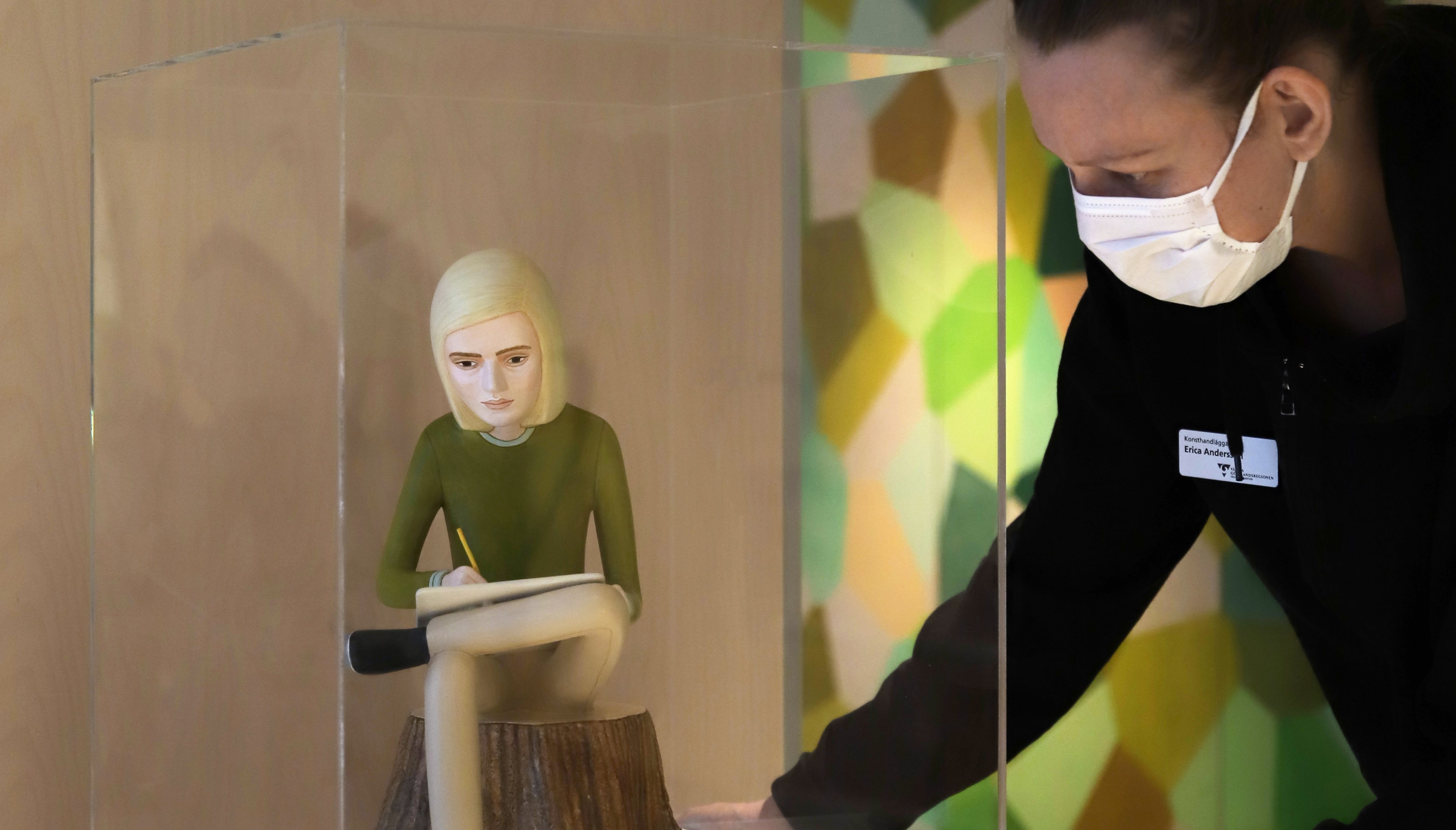 person i munskydd justerar konstverk