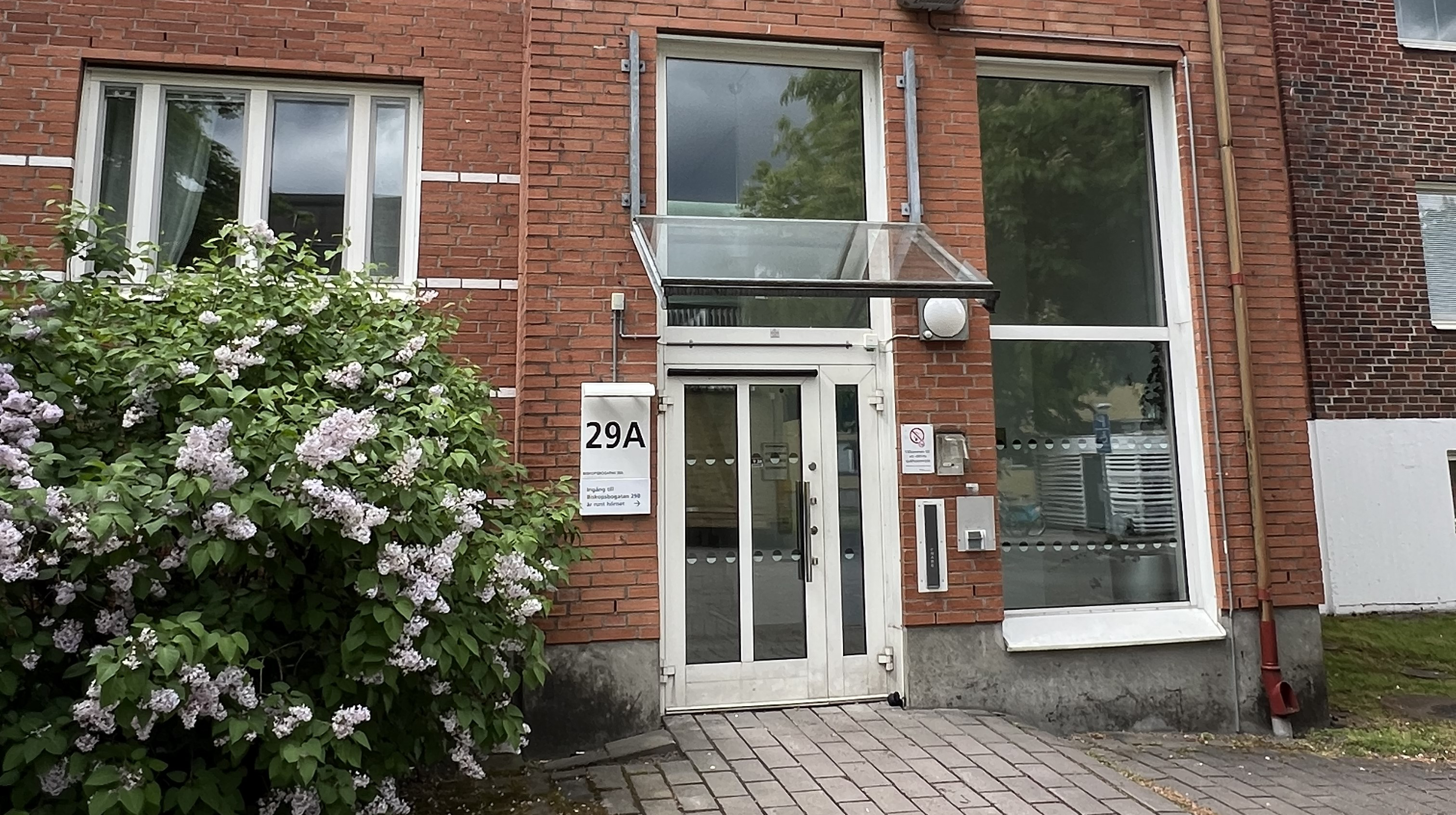 En vit dörr i en röd tegelbyggnad. Tydligt att det är ett sjukhus.